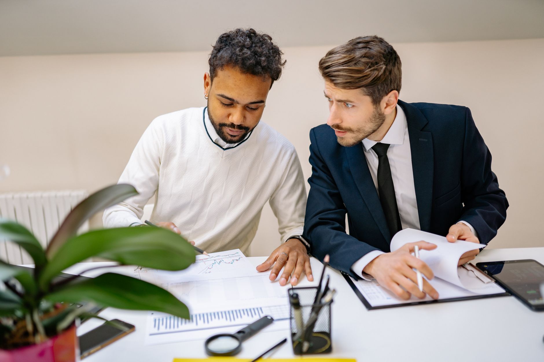 Two colleagues going through printed reports and a clipboard at a desk, the working shape of an audit interview.