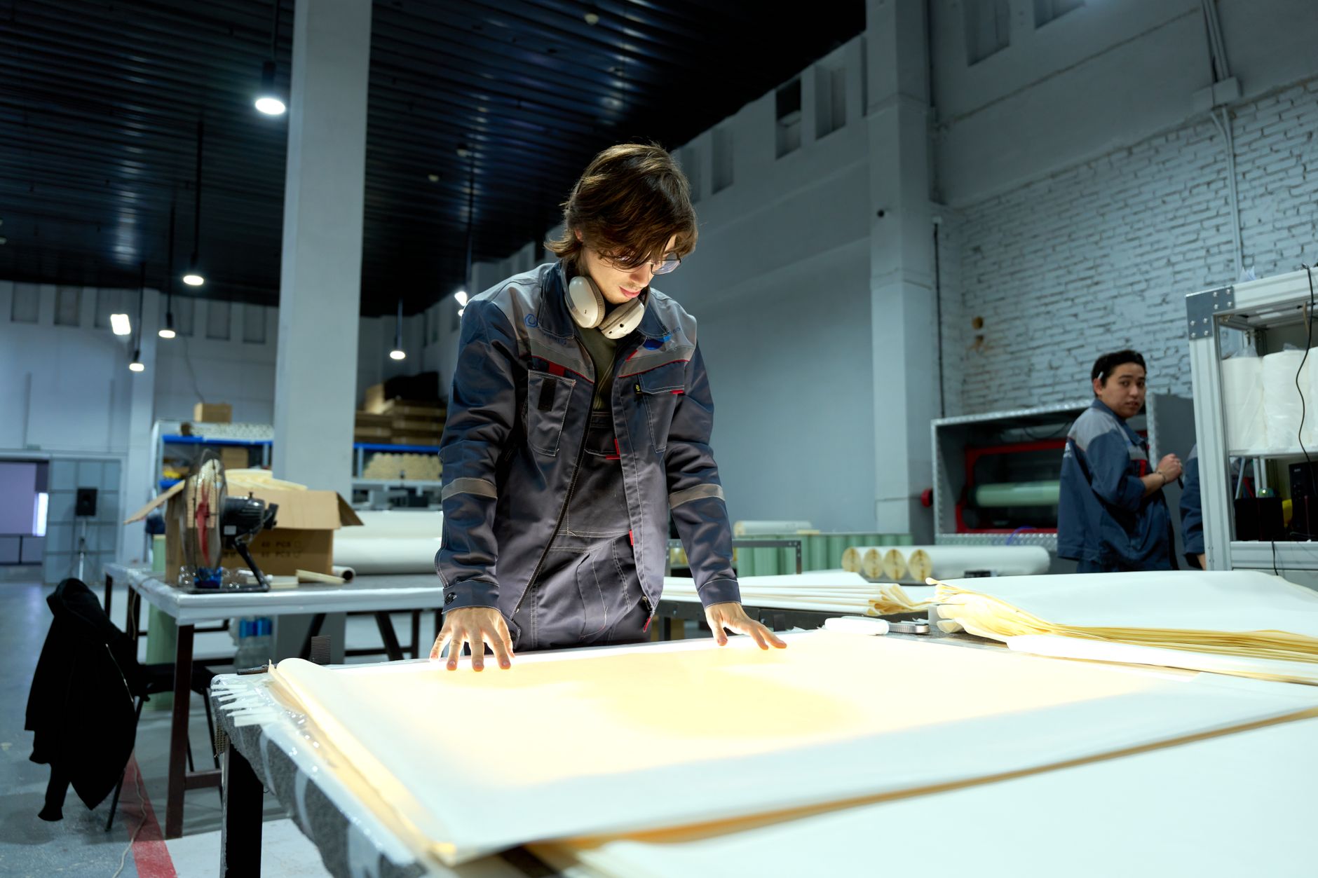 A worker inspecting sheet material on a factory floor — the consistency of output that ISO 9001 governs.