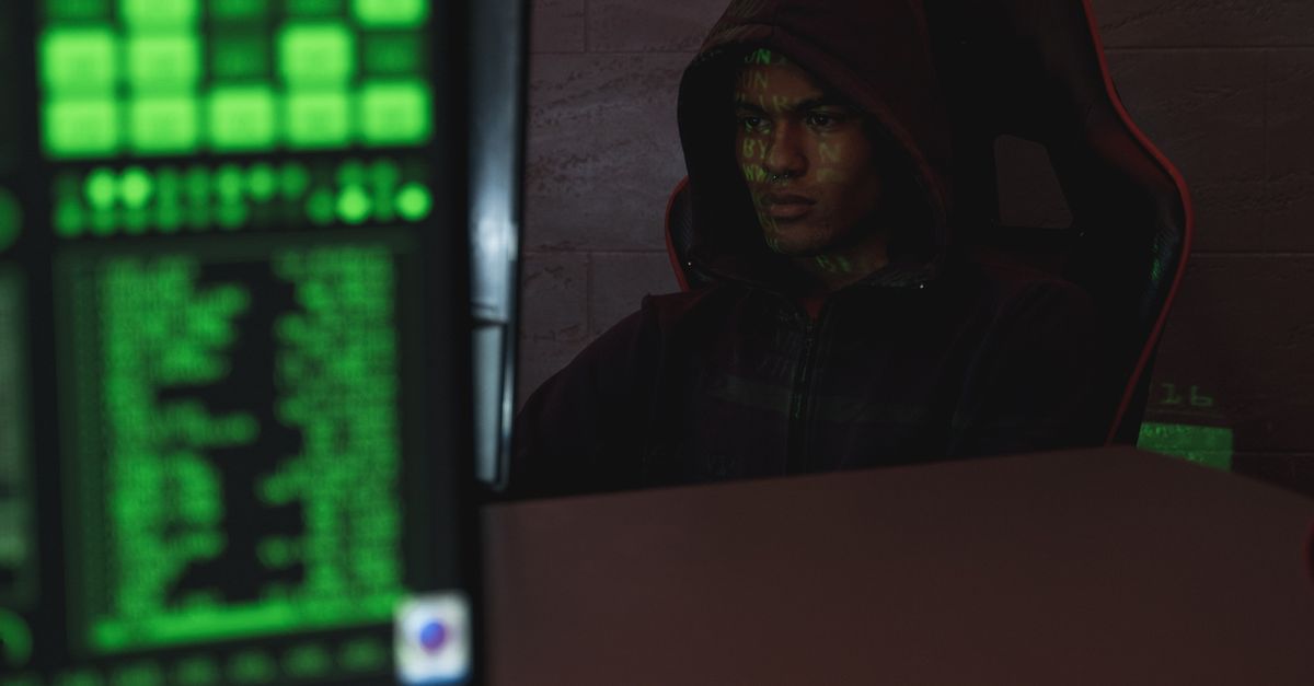 A hooded programmer focused on a screen — the adversary a SOC 2 penetration test simulates.