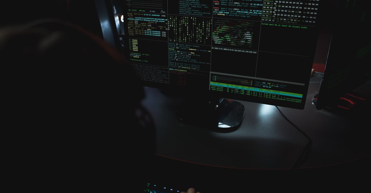 Code on dark monitors in a testing setup — the environment behind vulnerability assessment and penetration testing.