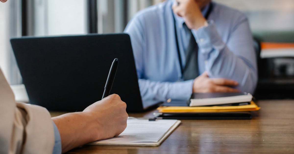Person signing a clipboard document at a dark wood desk — representing GDPR and CCPA privacy policy compliance.