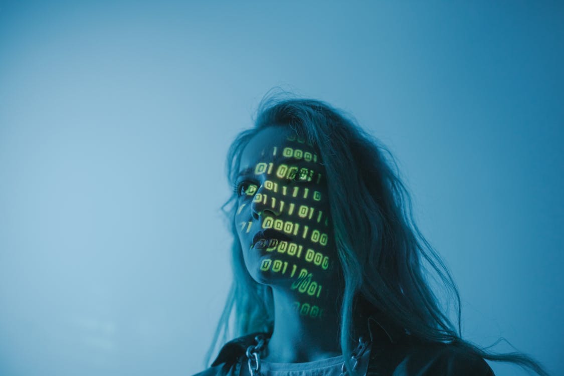Binary code projected on a face in blue light — representing ISO 27001 data governance for startups.