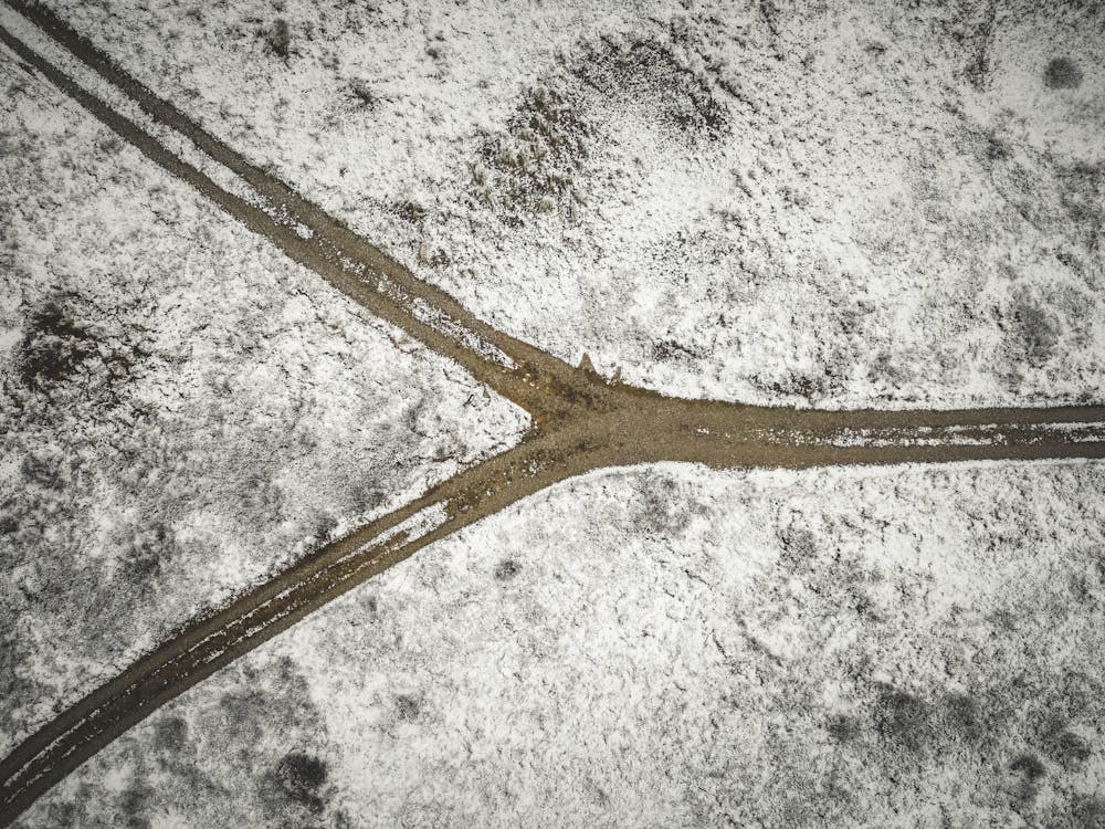 Aerial view of a snow-covered fork in a dirt road — representing the SOC 2 Type 1 vs Type 2 decision point.